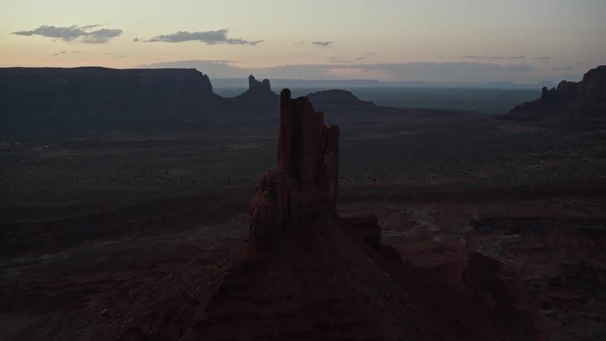 Rock formations and mesa stand on the desert landscape as the sun has set