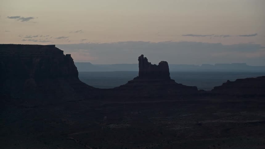 Clouds float by rock formation in silhouette