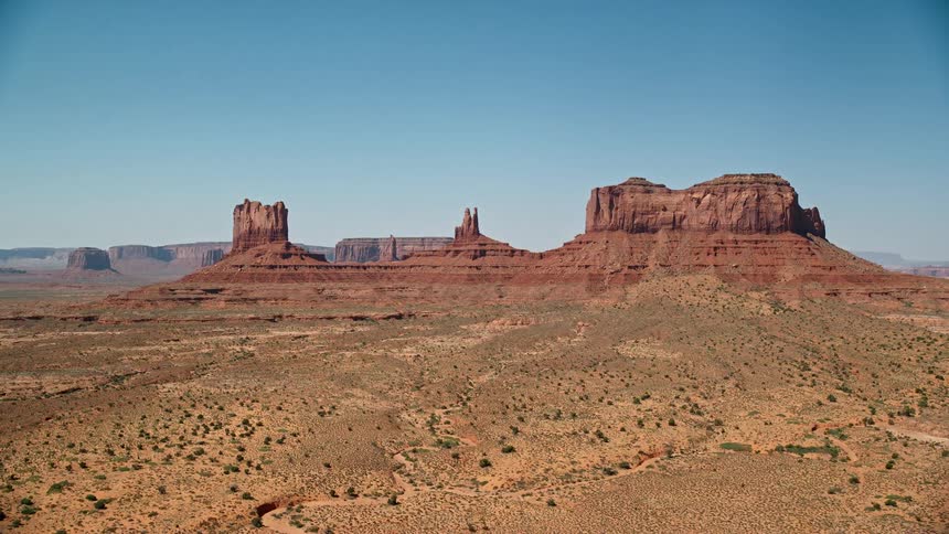 The sun shines upon rock formations and mesa on the desert landscape