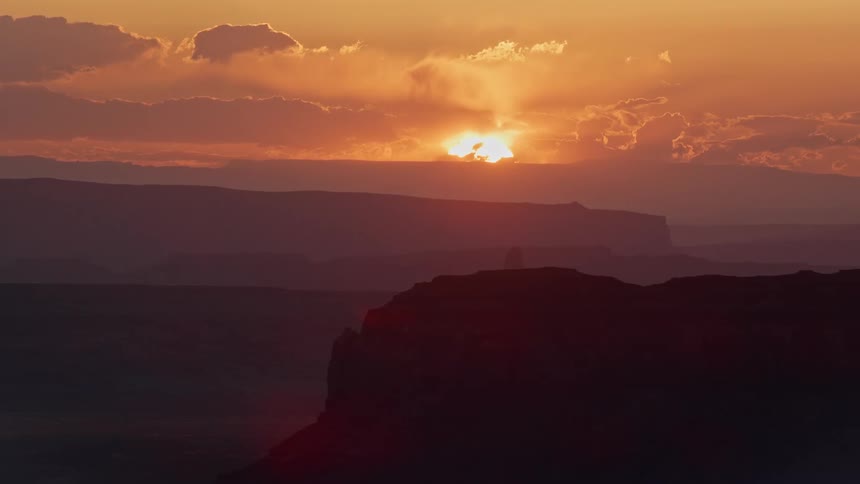 Sun rising over rugged mountains with canyons