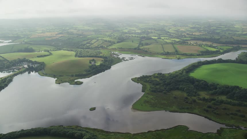 Fog covers several plots of land surrounding lakethat reflects clouds
