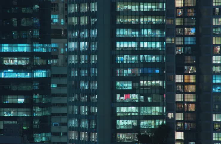 Exterior view of apartment buildings lights turning on at night