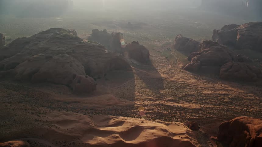 The hazy sun shining on sand dunes and buttes of monument valley