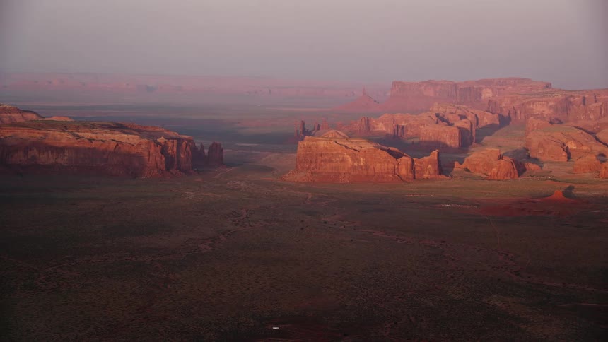 Aerial of mountain formations in the desert with a low flat land leading up to the mountain cliff