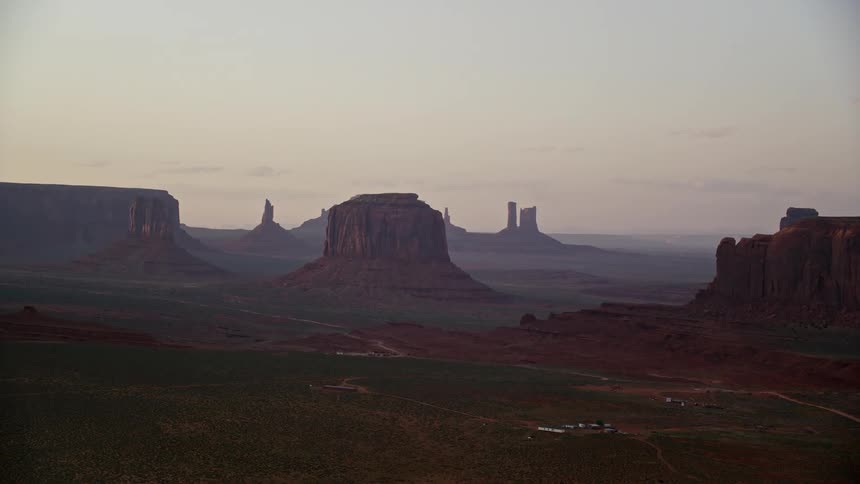 Aerial of a grassland valley with butte formations and mesa formed mountains in the desert during the day