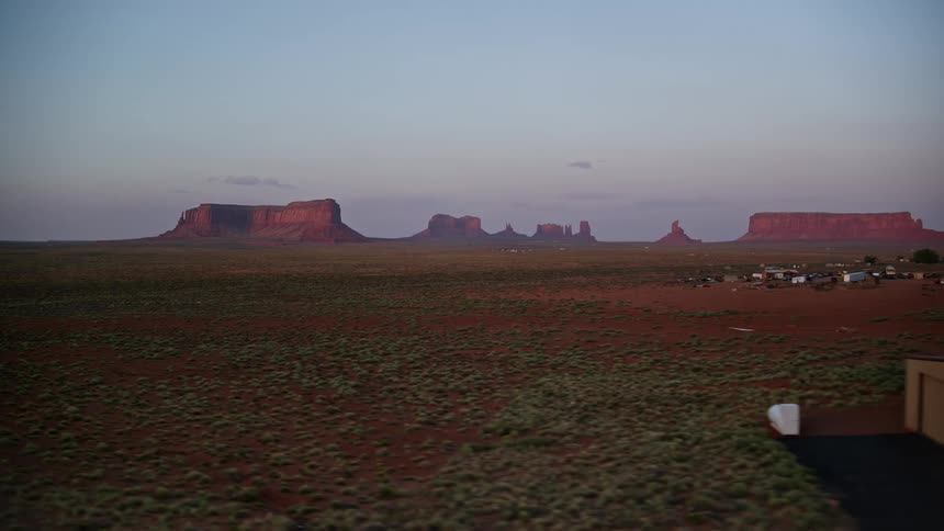 Drone view of flat lands in a rural area where few buildings are built and mountains on the horizon