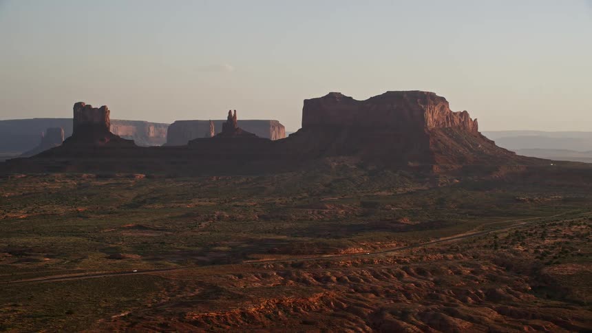 A desert region with canyons and rocky mountains and a road passing by