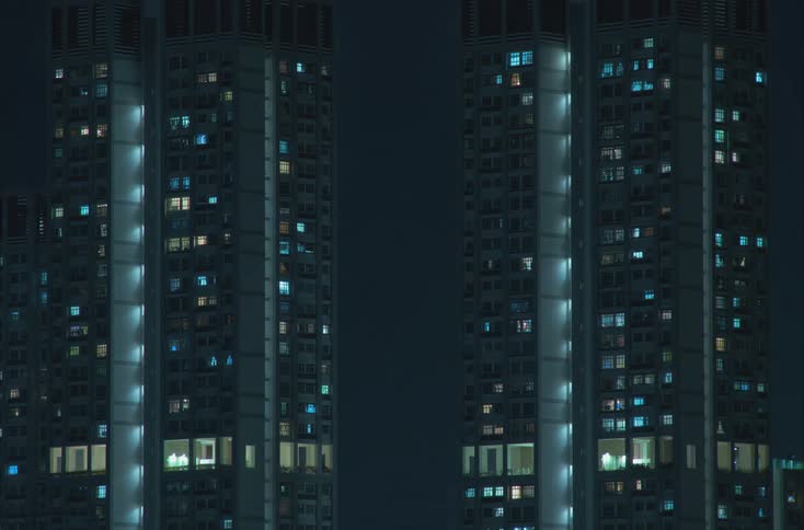 Some tall buildings have apartment lights being turned off as the night goes on