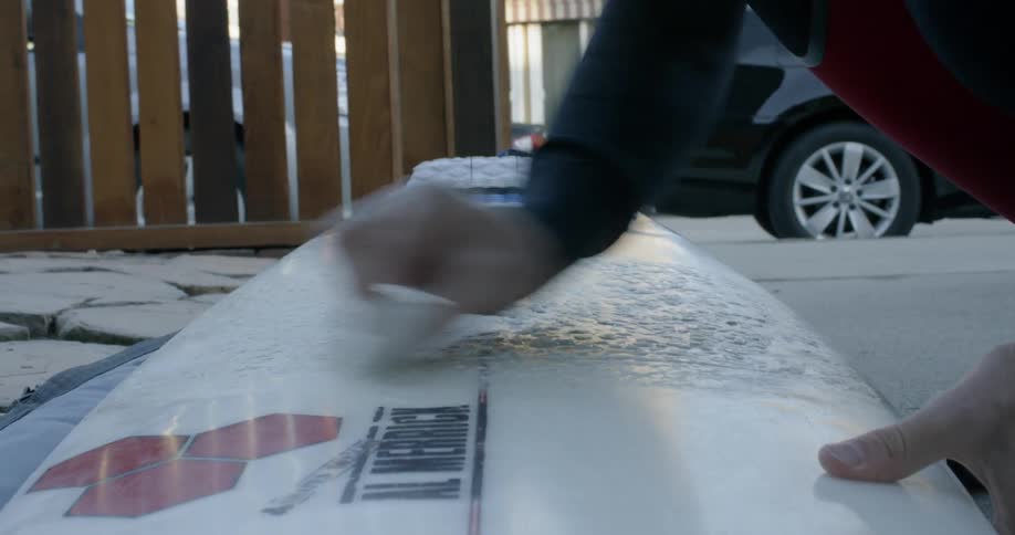 Man waxing up his surfboard