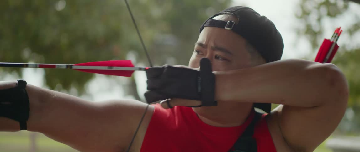 Archer takes aim and fires while standing in park