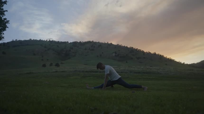 An adult man spreading his legs on a lawn to do a physical exercise position