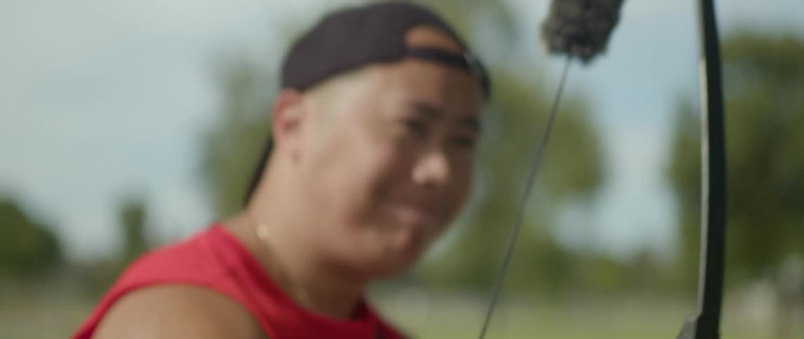 A man shoots an arrow at a target on a sunny day