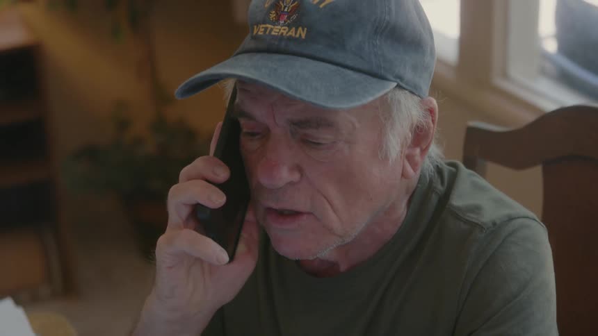 An elderly man is clearly upset while talking to someone on the phone