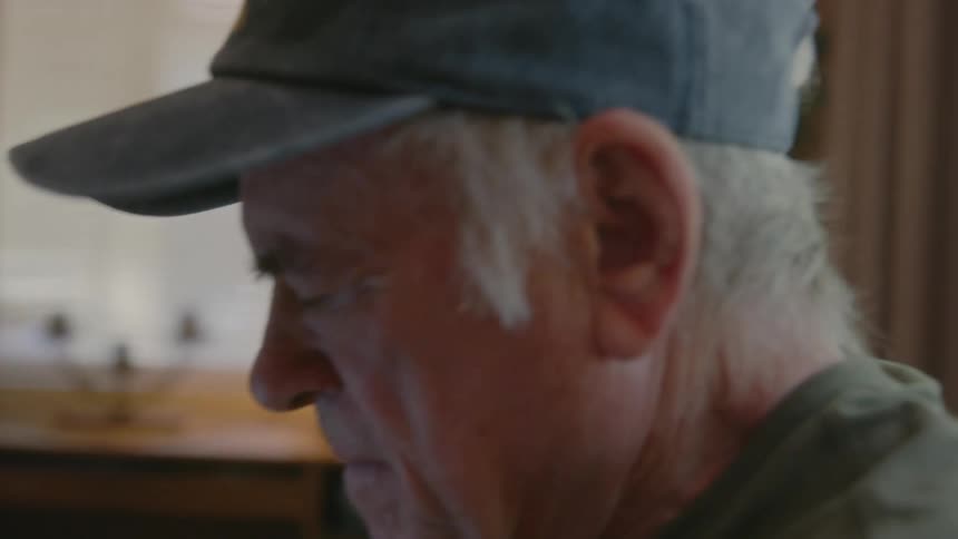 Elderly person sitting and typing on their laptop
