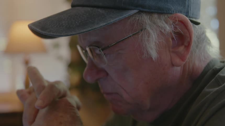 Elderly person picking up their glasses and putting them on
