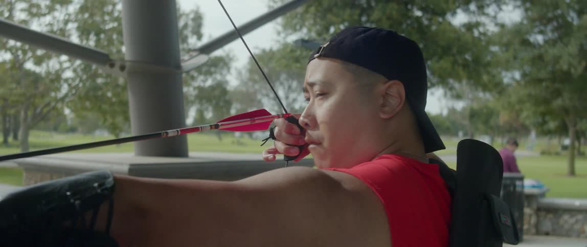 An asian man pulling a bowstring to shoot an arrow