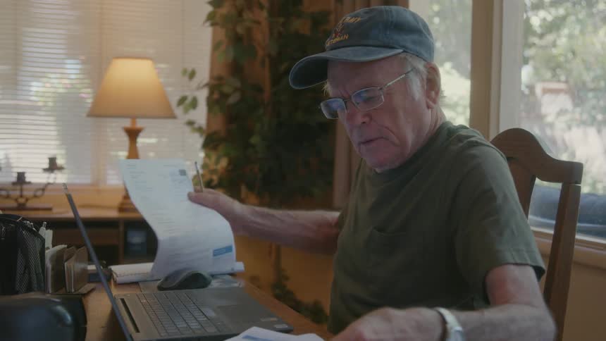 Senior citizen checks documents while working from home