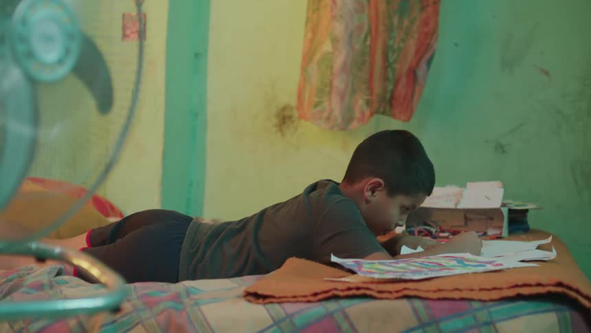 A child lying on a bed and drawing