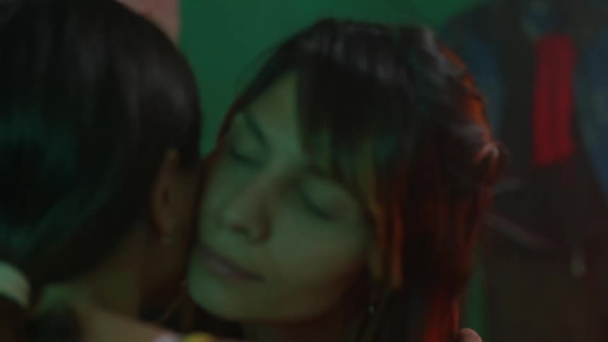 Two women greet each other with a kiss on the cheek and talk to each other