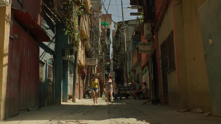 An alley full of houses and electricity wires where people pass by