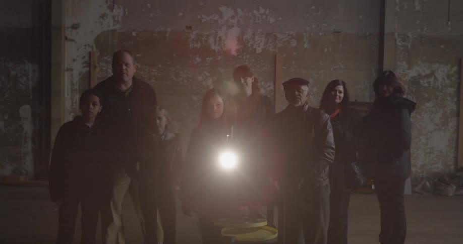 A group of people stand behind a projector watching