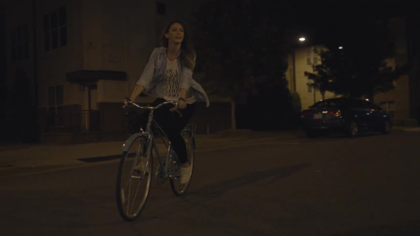 A woman is riding a bicycle at night