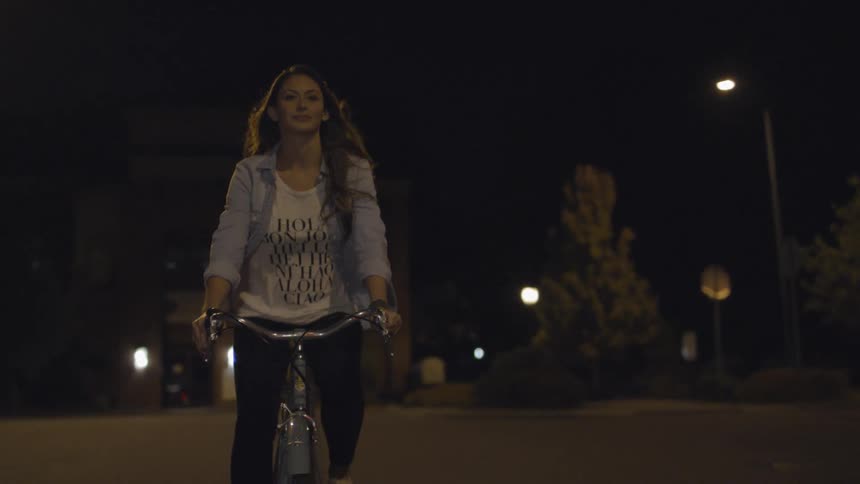 A woman is riding her bicycle at night
