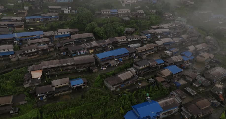 Drone view of third world housing structures built closely together as fog rolls in