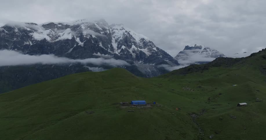 Aerial view of a farm in the green hills next to the mountains