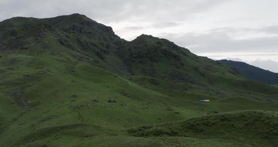 Aerial view of sheep on a farm in the green slopes of a mountain