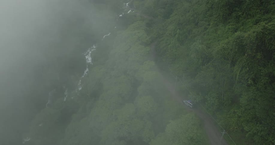 A car driving along a road in the middle of the forest with a stream in the middle