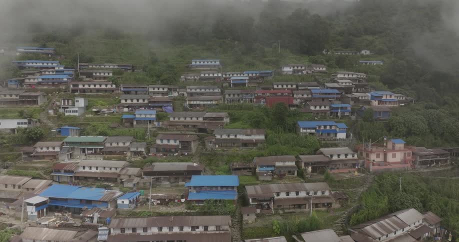 Aerial view of houses in the slopes of a mountain under the clouds