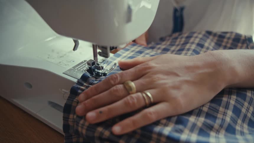 A lady sewing cloth indoor with a sewing machine