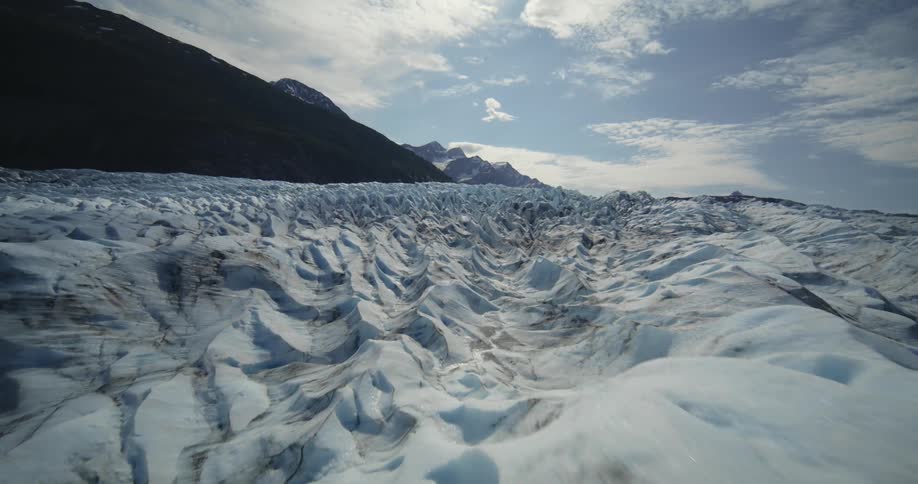 View of frozen ground with sharp formations and mountains in the background