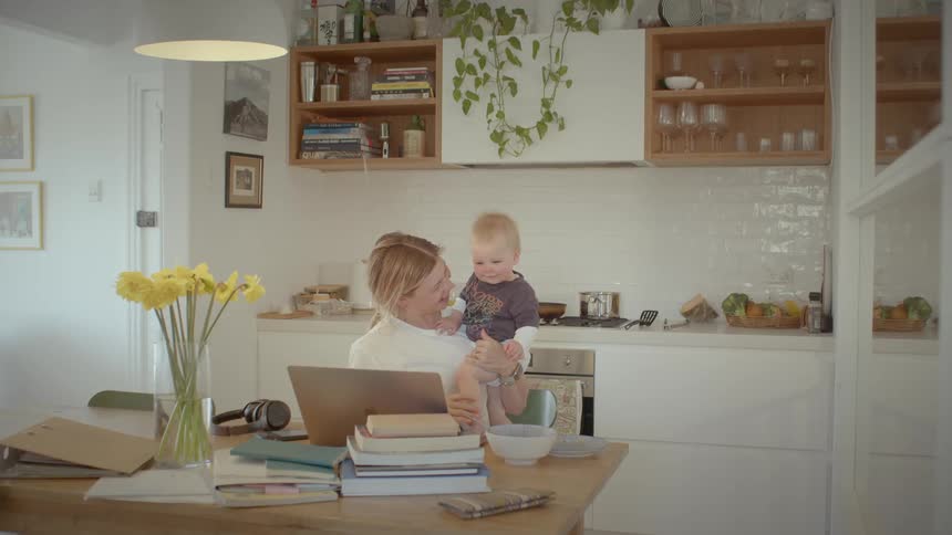 Mom laughs as she tries to teach baby to kisses at the laptop screen