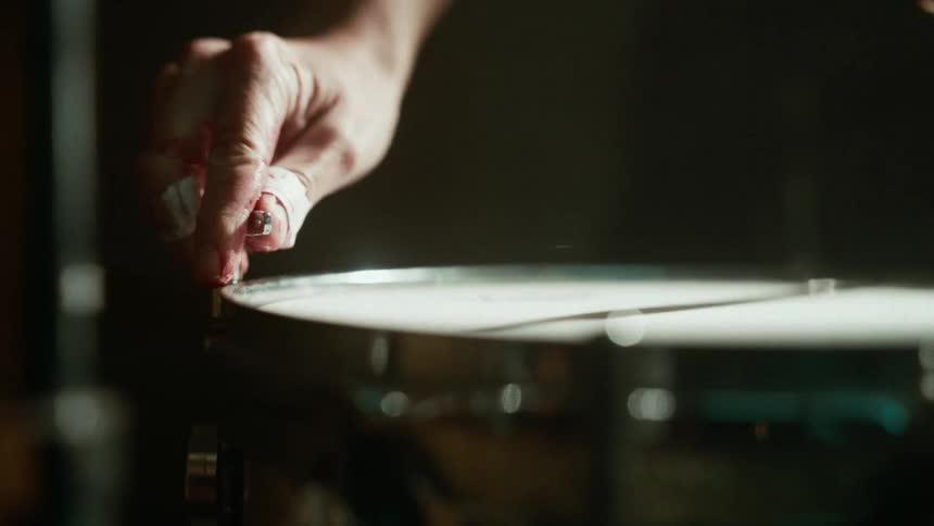 A person uses a special key to tune a drum