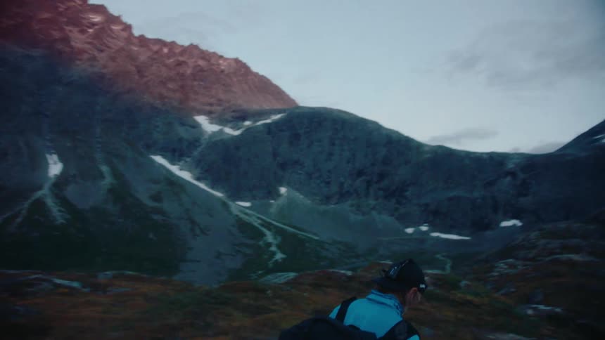 A mountaineer walks across a mountain ridge during the day