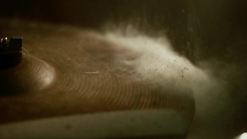 A drummer strikes a powder covered cymbal