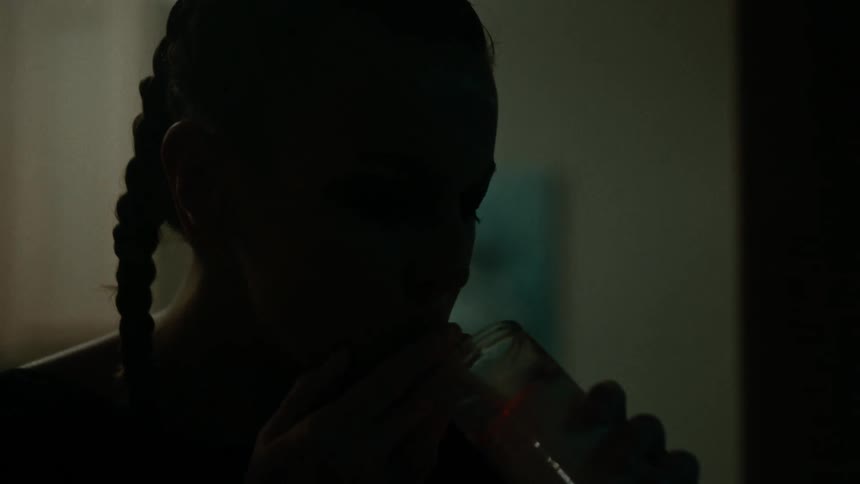A woman with braided hair uses a candle to light her cigarette and the candle goes out