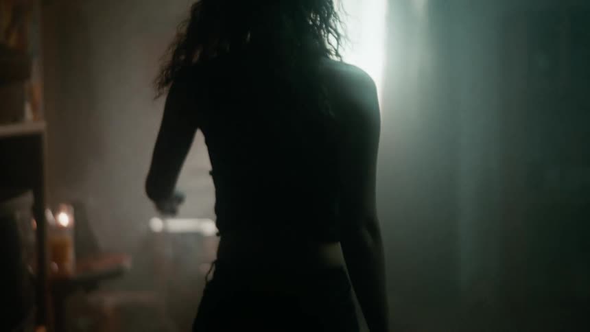 A woman walking towards a musical instrument a drum set with her back turned