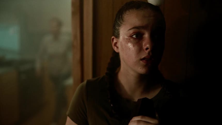 Girl with braids and dark green t shirt cries and hides behind a wall