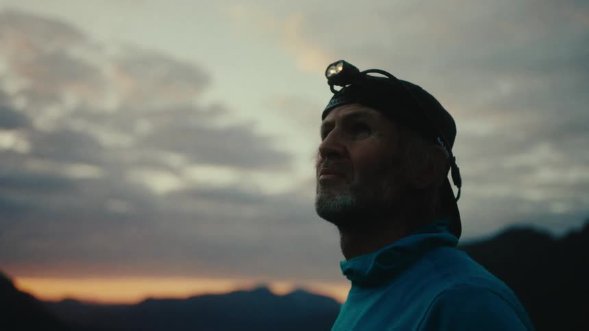 A standing man with headlight looking around at sunset