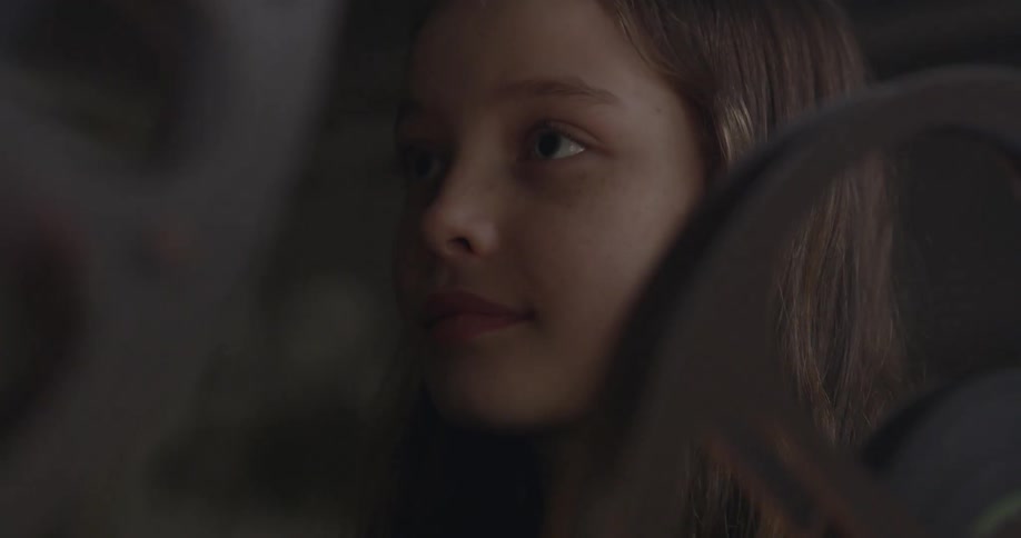 A girl smiles next to spinning film reels