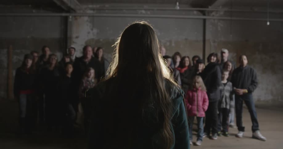 A girl stands in front of a projector as a group watches