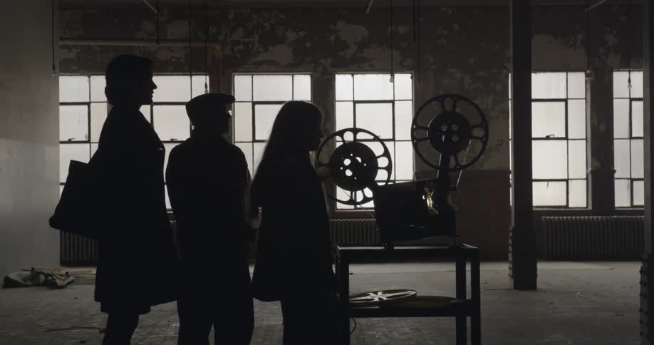 Three people stand behind an old projector