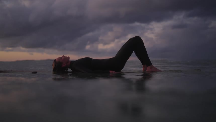 Beautiful young women lying on surf board.