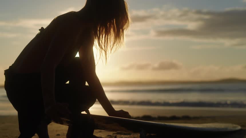A woman squatting and playing with the sand at the beach
