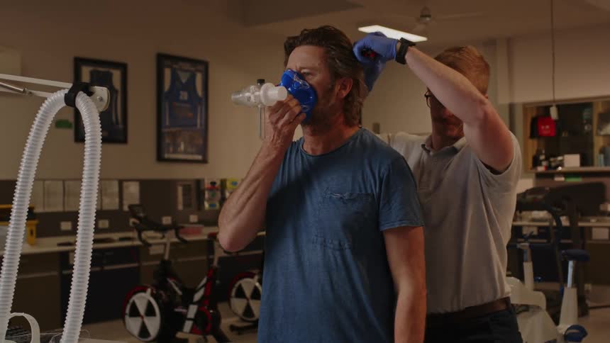 An health specialist assisting a man in wearing an health mask