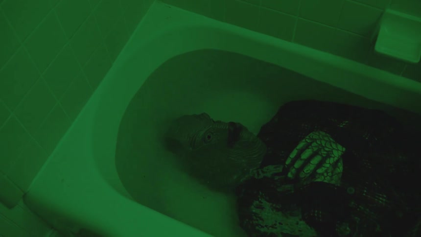 Person with mask on head lying in a bathtub of water