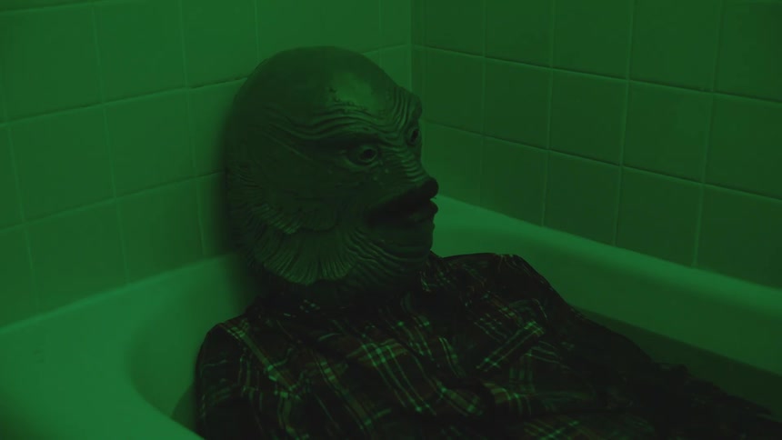 A person wearing a strange mask in the bathtub
